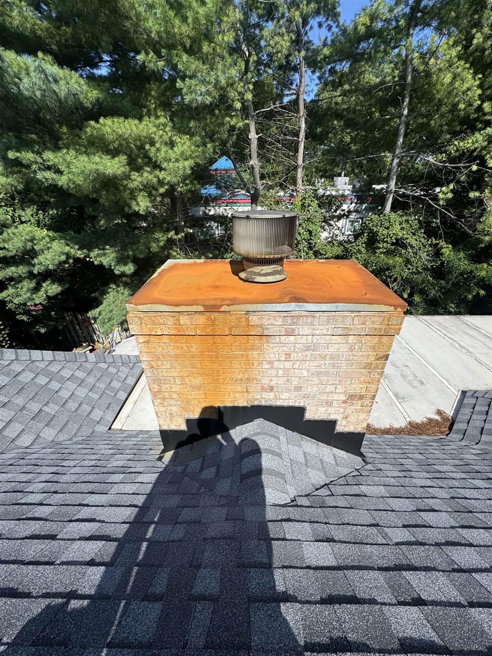 Rusted chase cover on a brick chimney with orange stains running down the brick — Louisville, KY