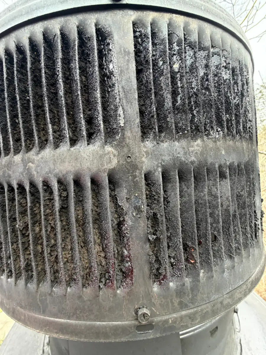 Expanded carbonized creosote choking the chimney cap screen after a hidden chimney fire — Crestwood, KY