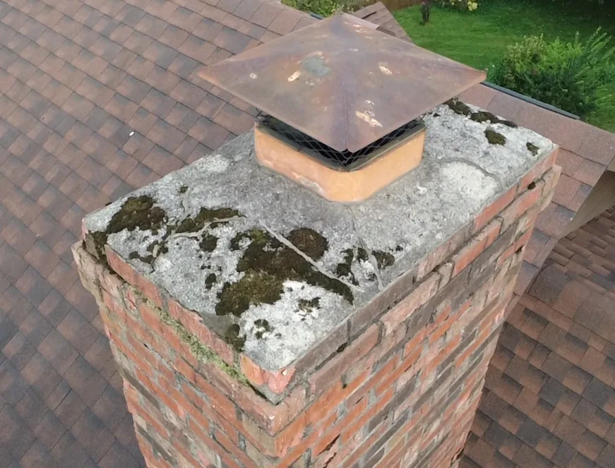 Top-down view of a cracked, moss-covered concrete chimney crown with a metal cap — Lake Forest Parkway, Middletown, KY